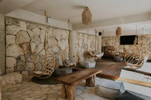 a stone walled bathroom with a wooden table and two toilets at Cenote + Swim-Up + Luxury Condo in Tulum