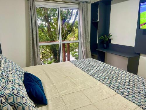 um quarto com uma cama e uma grande janela em Mar Rio casa de praia em Piçarras