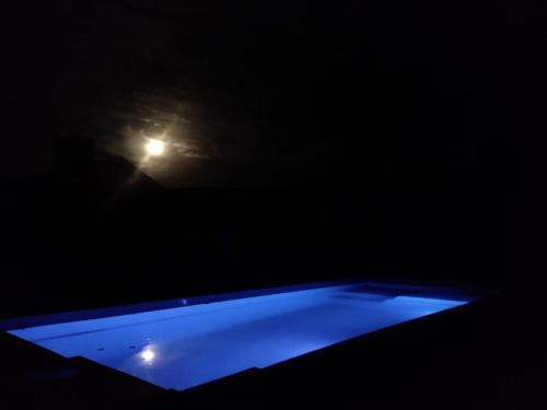 a blue pool in the dark with a light in the background at Maika in Sierra de la Ventana