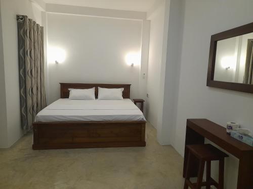 a bedroom with a bed and a mirror and a table at Gloria Inn in Negombo