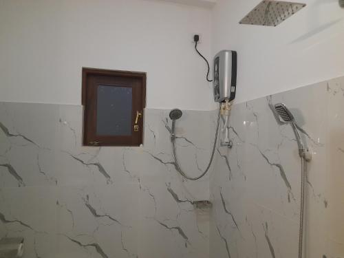 a bathroom with a shower with a phone on the wall at Gloria Inn in Negombo