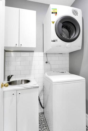 a white bathroom with a washing machine and a sink at The Grande Port Stephens Luxurious golf and beach getaway on Horizons Golf Resort in Salamander Bay