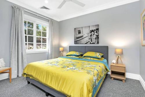 Un dormitorio con una cama amarilla y una ventana en The Grande Port Stephens Luxurious golf and beach getaway on Horizons Golf Resort, en Salamander Bay