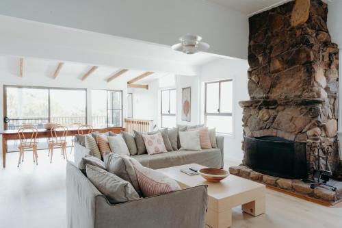 a living room with a couch and a stone fireplace at Massinger Views in Byron Bay