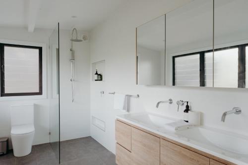 Un baño blanco con lavabo e inodoro. en Massinger Views, en Byron Bay