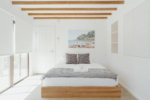 Un dormitorio con una cama en una habitación blanca. en Massinger Views, en Byron Bay