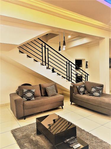 a living room with two couches and a staircase at Entire Serviced Two bedroom duplex Abuja - 24hr WIFI, POWER, OFFICE, FULL KITCHEN in Abuja