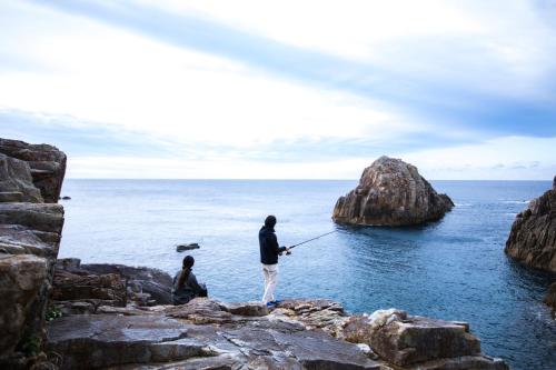 a man and a woman fishing on the rocks at TheMana Village in Tosashimizu