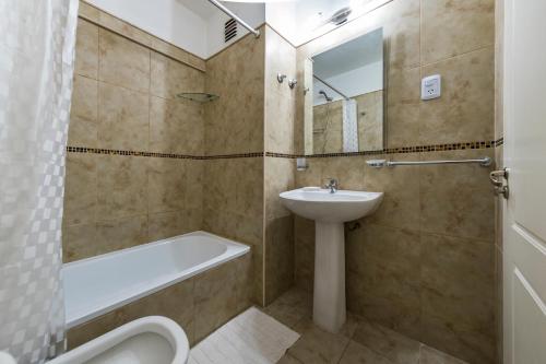 a bathroom with a sink and a tub and a toilet at Emilio Olmos 491 - B Centro Edificio con Pileta y Vistas al Rio in Cordoba