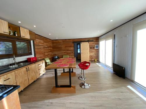a kitchen with a wooden table and a red stool at Cabaña Pampa Pinuer Coyhaique in Coihaique