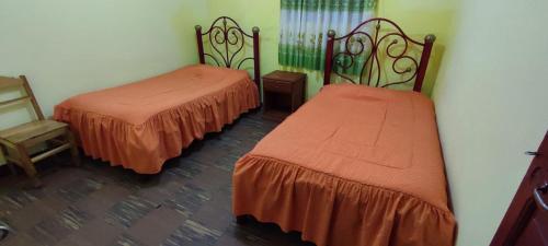 a room with two beds and a chair at Alojamiento la Gran Estación in Uyuni