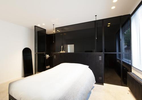 a bedroom with a white bed and a black wall at Logieslogees in Tielrode