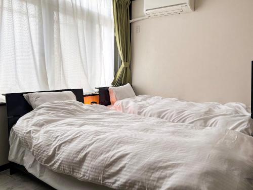 two unmade beds in a bedroom with a window at Noah's Ark78 The Guesthouse Noah in Naha