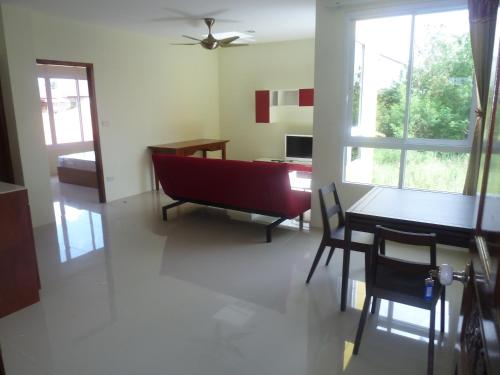 a living room with a red couch and a table at Gib Apartment in Surin