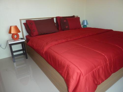 ein Bett mit einer roten Decke und einem Beistelltisch in der Unterkunft Gib Apartment in Surin