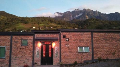 a brick building with a mountain in the background at KOMOWANAN HOMESTAY in Kundasang