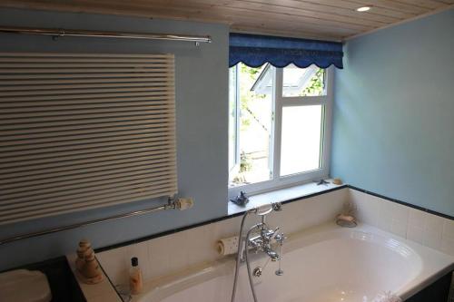 a bath tub in a bathroom with a window at Enniskerry - The Loves Cottage in Shepton Mallet