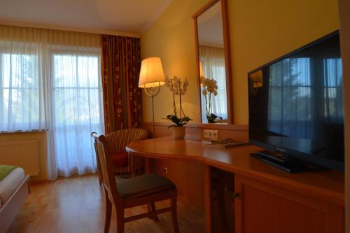 ein Hotelzimmer mit einem TV und einem Schreibtisch mit einem Stuhl in der Unterkunft Peterwirt in Bad Mitterndorf