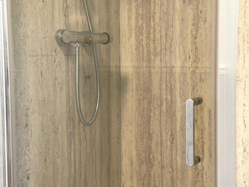 a shower with a shower head on a wooden wall at West View in Ripon