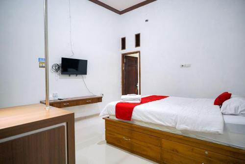 um quarto com uma cama e uma televisão em RedDoorz at Jalan Basuki Rahmat Lampung em Lampung
