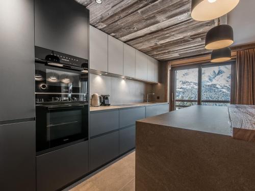 une cuisine avec des placards gris et un comptoir dans l'établissement Superbe appartement skis aux pieds avec conciergerie 5*, Méribel - FR-1-613-64, à Les Allues