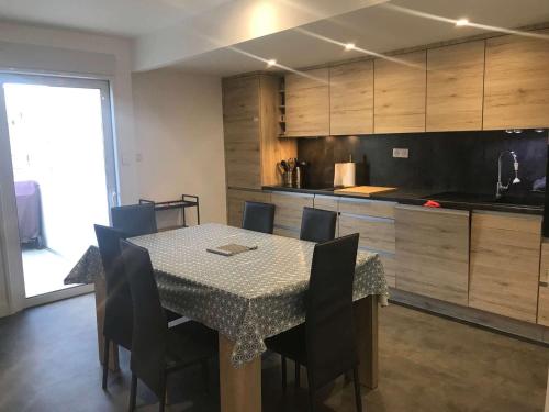 une salle à manger avec une table et des chaises et une cuisine dans l'établissement Bel Appartement Cœur de Ville, 6 Pers, Terrasse, Clim, Parking, à 400m de la Plage - FR-1-701-7, à Valras-Plage