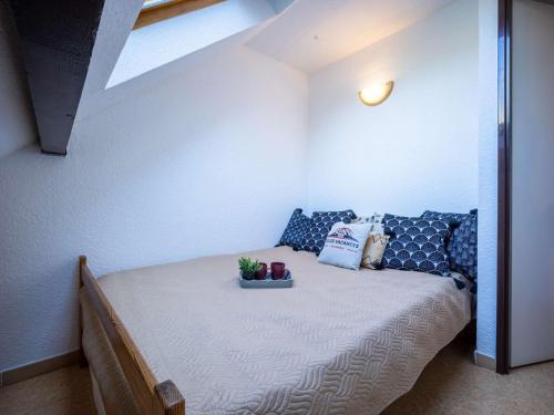 a small bedroom with a bed with blue pillows at Appartement 4 pers, St Lary, animaux acceptés - FR-1-296-456 in Saint-Lary-Soulan