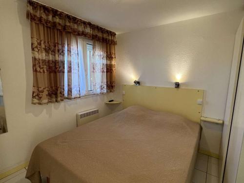 een kleine slaapkamer met een bed en een raam bij Appartement Valras-Plage, 1 pièce, 4 personnes - FR-1-701-21 in Valras-Plage