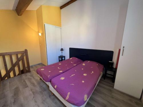 małe łóżko w pokoju z fioletowym prześcieradłem w obiekcie Pavillon 4 pers avec piscine, terrasse, parking, à 700m de la plage et proche commerces - FR-1-701-20 w mieście Vendres