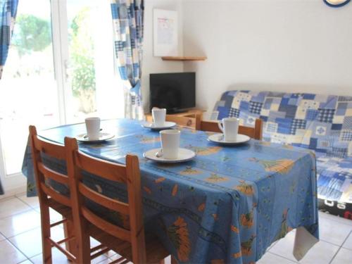 une table à manger avec des chaises et un chiffon bleu dans l'établissement Maison cosy avec terrasse, 2 chambres, piscine partagée, proche plage et commerces, Gruissan - FR-1-229-832, à Gruissan