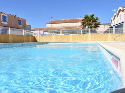 basen z niebieską wodą przed budynkiem w obiekcie Maison cosy avec terrasse, 2 chambres, piscine partagée, proche plage et commerces, Gruissan - FR-1-229-832 w mieście Gruissan