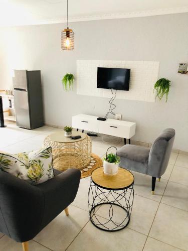 a living room with two chairs and a tv at Zinathi Lodge in Lebowakgomo