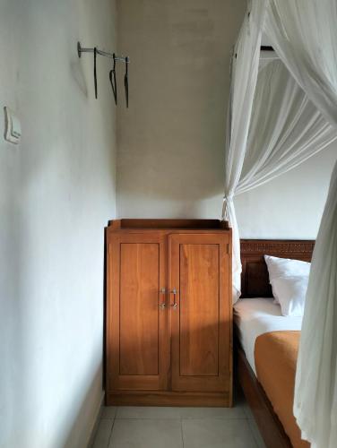 a bedroom with a canopy bed and a wooden cabinet at Made Oka Homestay and Warung in Munduk