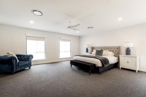 a bedroom with a bed and a chair and windows at Whitevale Luxury Estate in Lovedale