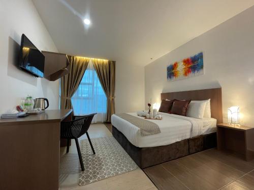 a bedroom with a bed and a desk and a television at DSH Hotel in Kuantan