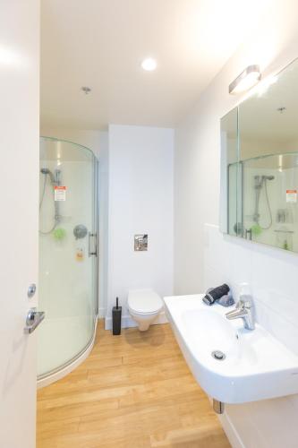 a white bathroom with a shower and a sink at Ocean Eleven 4 in Mount Maunganui