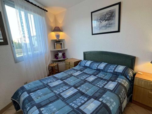 een slaapkamer met een bed met een blauw dekbed en een raam bij Appartement Valras-Plage, 2 pièces, 6 personnes - FR-1-701-38 in Valras-Plage