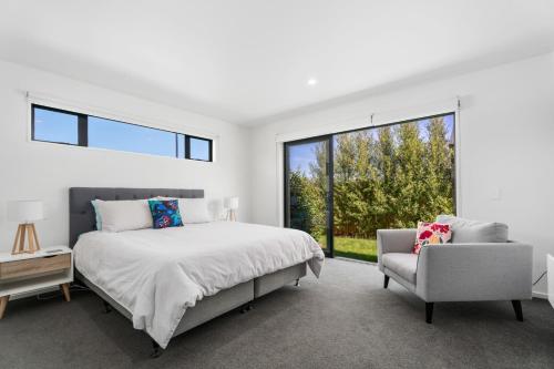 a bedroom with a bed and a chair and a window at Northlake Hideaway - Wanaka Holiday Home in Wanaka