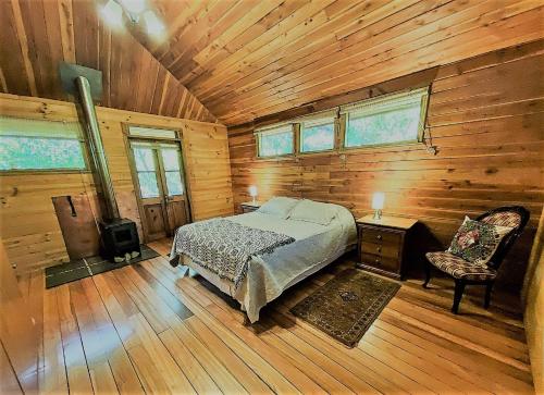 1 dormitorio en una cabaña de madera con 1 cama y 1 silla en Casa La Montaña, en San José de Maipo