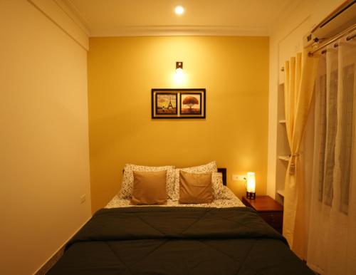 a bedroom with a bed with yellow walls at AVANTI CASTELLO in Guruvāyūr