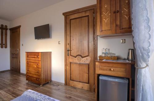 a room with a wooden door and a kitchen with wooden floors at Willa Góralski Styl in Bukowina Tatrzańska