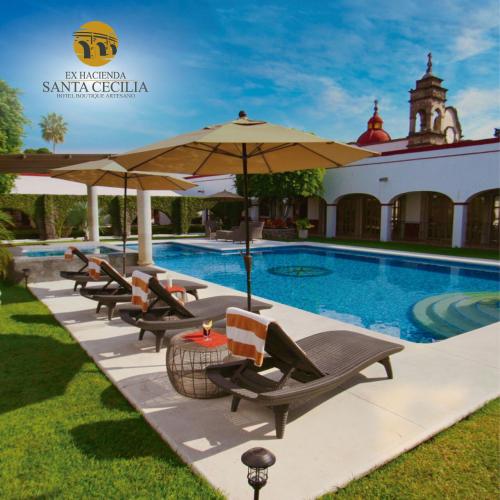 a row of chairs and umbrellas next to a swimming pool at Ex Hacienda Santa Cecilia in Cuernavaca