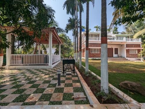 a bench in front of a house with palm trees at Sundeck Villa in Alibaug