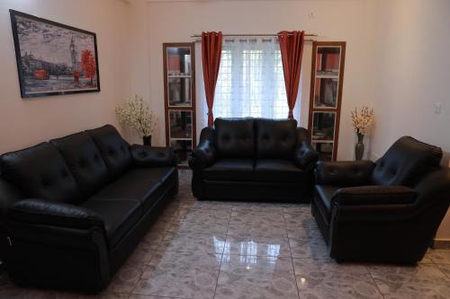 a living room with two black leather couches at AVANTI CASTELLO in Guruvāyūr