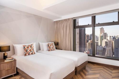 a bedroom with a white bed and a large window at Shama Central in Hong Kong