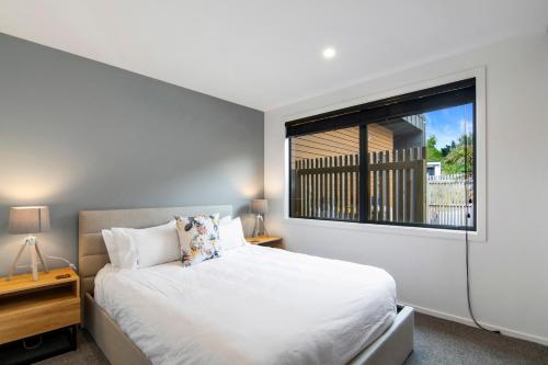 a bedroom with a white bed and a window at Kotuku Apartment - Kaiteriteri Holiday Unit in Kaiteriteri