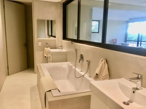a white bathroom with a tub and a sink at Klein Windhoek Garden flat in Windhoek