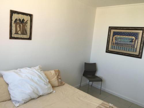 a bedroom with a bed with a chair and a painting at City Junction in Windhoek
