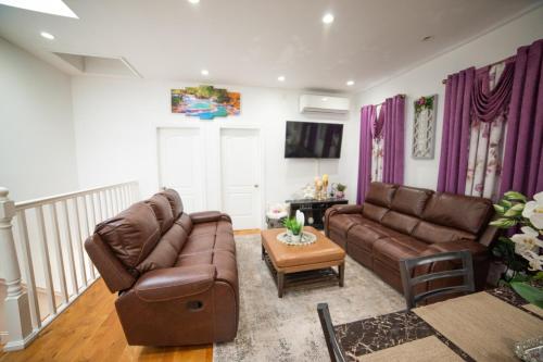 a living room with two brown leather couches and a table at Top Floor with Skylight Brooklyn in Brooklyn