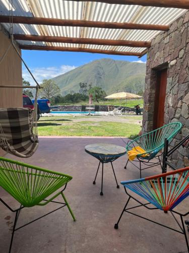 3 Stühle und ein Tisch auf einer Terrasse mit Bergen in der Unterkunft Santuyoc Lodge in Volcán